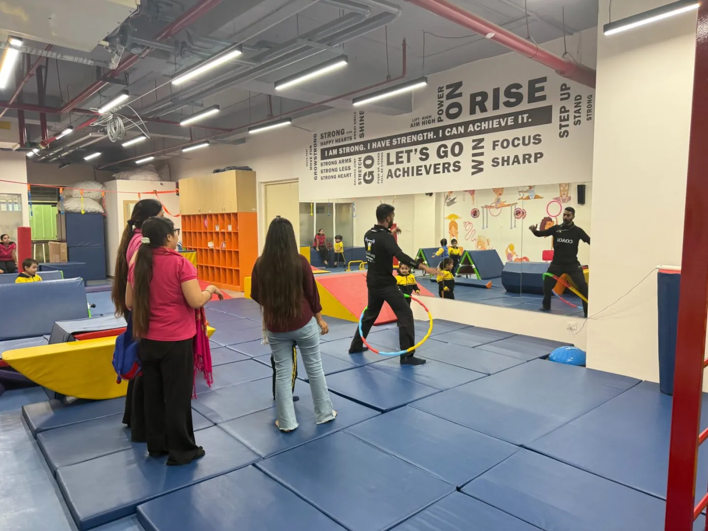 A coach taking a gymnastics session with children on the mats