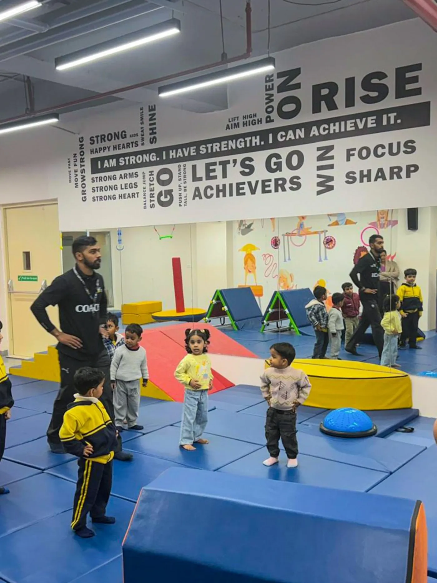 A coach greeting a group of young children at the start of a session